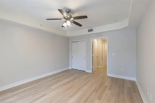 an empty room with wooden floor closet and fan