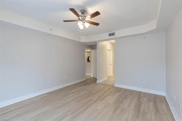 an empty room with wooden floor and ceiling fan