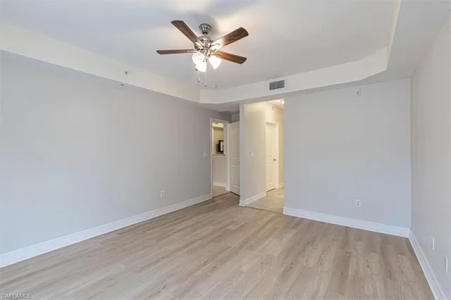 an empty room with wooden floor and ceiling fan