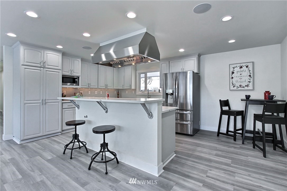 8925 Lake Steilacoom Point Road Southwest Lakewood, WA 98498 - Photo 14 of 31 a kitchen with refrigerator a table and chairs in it