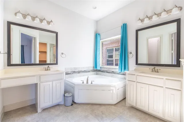 a bathroom with a bathtub a double vanity sink and mirror