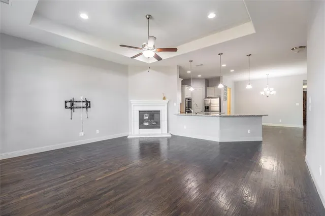 an empty room with wooden floor and kitchen view