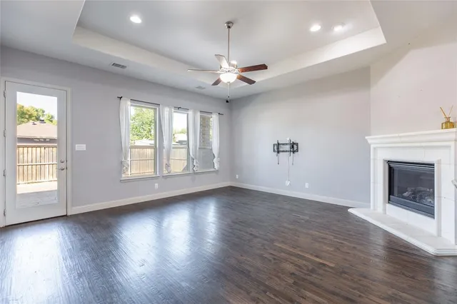 an empty room with wooden floor chandelier and windows
