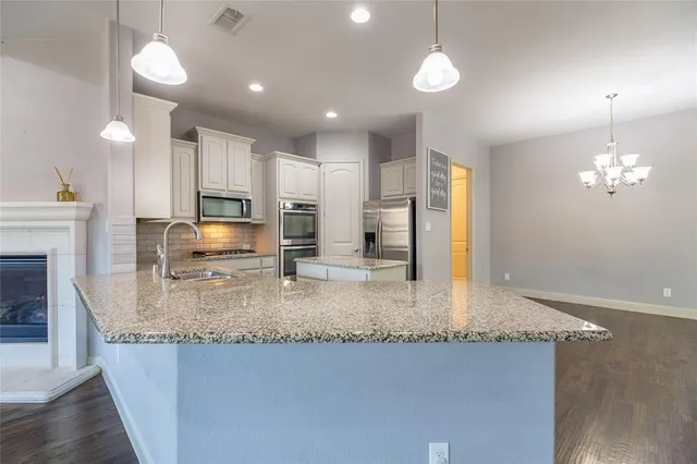 a kitchen with kitchen island granite countertop stainless steel appliances a stove a refrigerator a oven and a sink with granite countertops