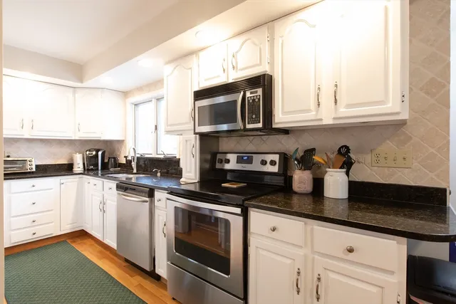 a kitchen with granite countertop white cabinets and appliances