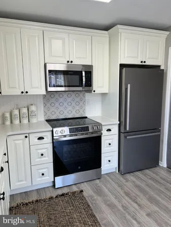 a kitchen with stainless steel appliances granite countertop a refrigerator stove and white cabinets