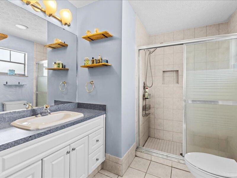 1297 Southeast Floresta Drive Port St. Lucie, FL 34983 - Photo 17 of 42 a bathroom with a granite countertop sink a toilet and shower