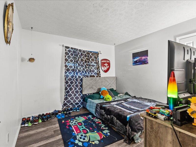 1297 Southeast Floresta Drive Port St. Lucie, FL 34983 - Photo 24 of 42 a bedroom with a bed and a wooden floor