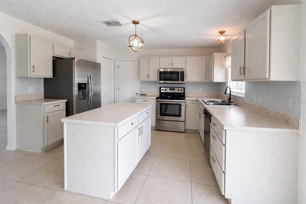 704 Swan Way Kissimmee, FL 34758 - Photo 4 of 15 a kitchen with stainless steel appliances a refrigerator sink and microwave