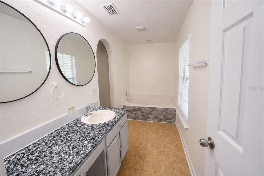 704 Swan Way Kissimmee, FL 34758 - Photo 7 of 15 a bathroom with a granite countertop sink a toilet and a mirror