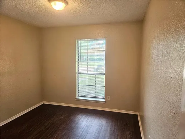 an empty room with wooden floor and window