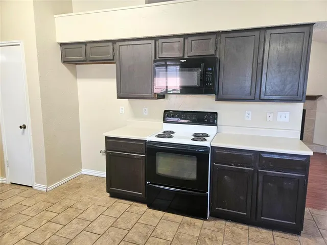 a kitchen with granite countertop a stove top oven and cabinets