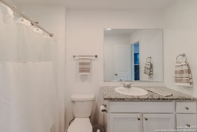 a bathroom with a granite countertop sink a mirror and a toilet