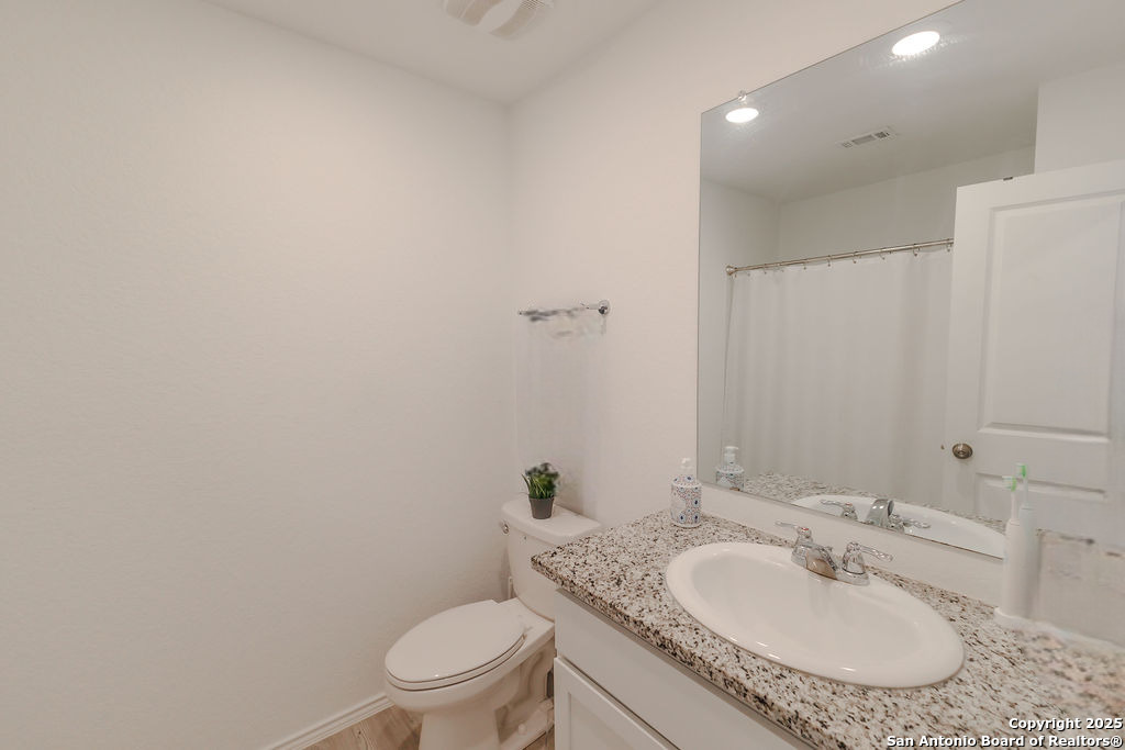 10502 Torroja Way Converse, TX 78109 - Photo 23 of 35 a bathroom with a granite countertop sink a toilet and a mirror