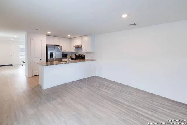 a kitchen with granite countertop a stove top oven and cabinets