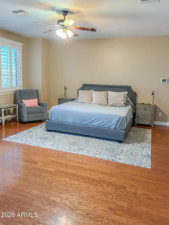 a spacious bedroom with a bed a dresser and wooden floor