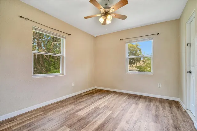 a view of an empty room with a window and wooden floor