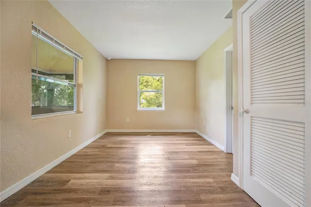 a view of an empty room with window and wooden floor