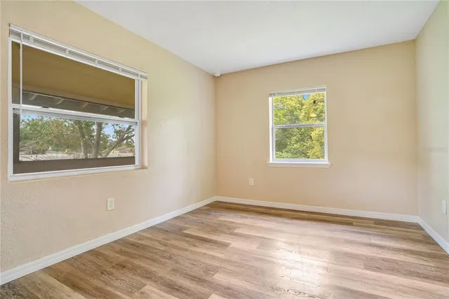 a view of an empty room with wooden floor and a window
