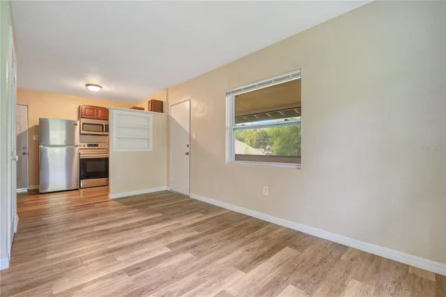 a view of a kitchen with a fridge wooden floor and a window