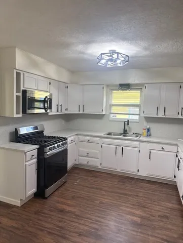 a large kitchen with stainless steel appliances granite countertop a stove a sink dishwasher and a microwave oven with wooden floor