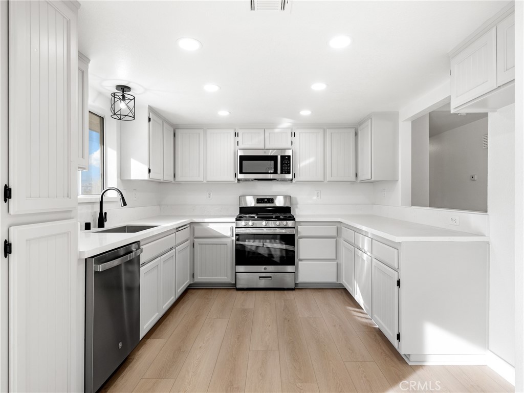 12780 Hacienda Road Phelan, CA 92371 - Photo 13 of 38 a kitchen with granite countertop white cabinets and stainless steel appliances