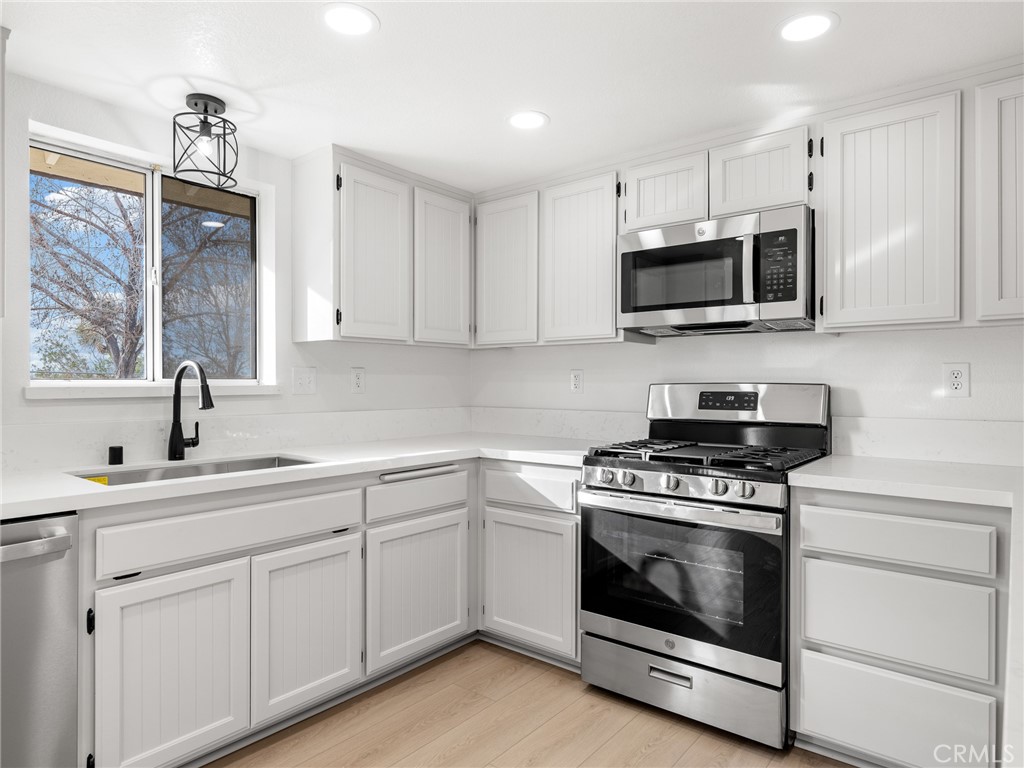 12780 Hacienda Road Phelan, CA 92371 - Photo 14 of 38 a kitchen with white cabinets and stainless steel appliances