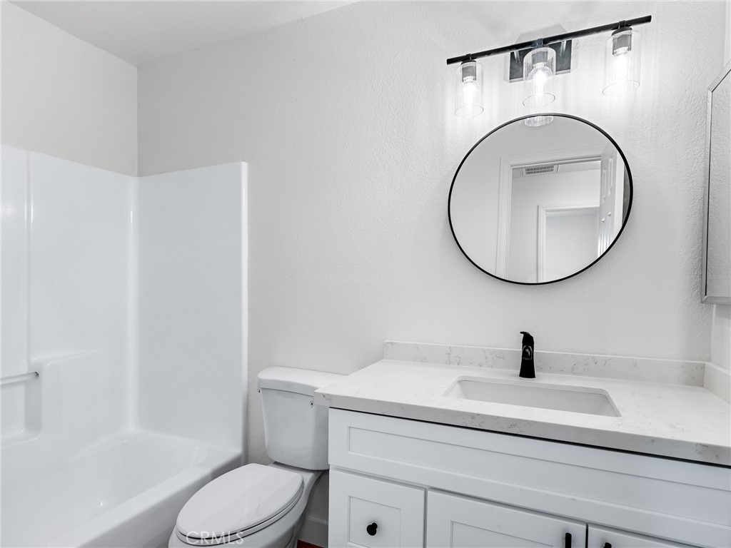 12780 Hacienda Road Phelan, CA 92371 - Photo 16 of 38 a bathroom with a toilet a sink and a mirror