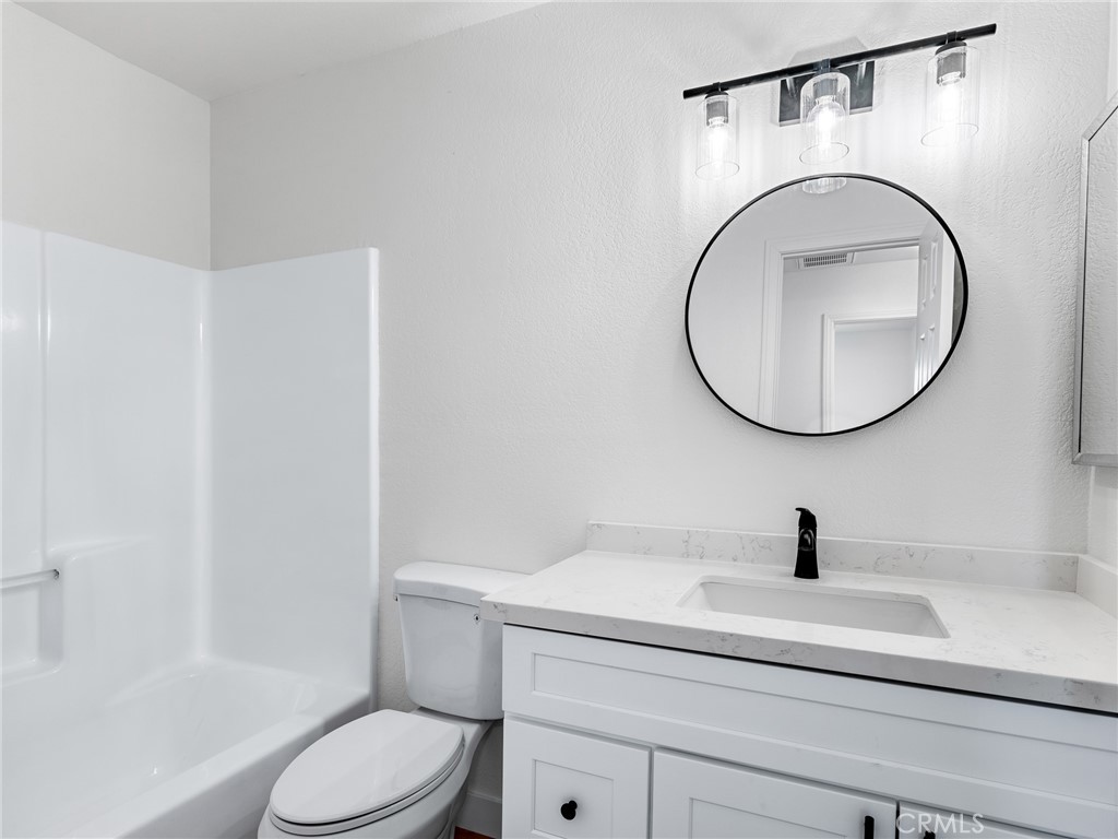 12780 Hacienda Road Phelan, CA 92371 - Photo 16 of 38 a bathroom with a toilet a sink and a mirror