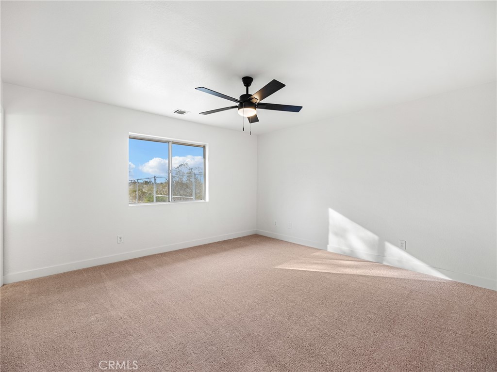 12780 Hacienda Road Phelan, CA 92371 - Photo 19 of 38 an empty room with a ceiling fan and a window