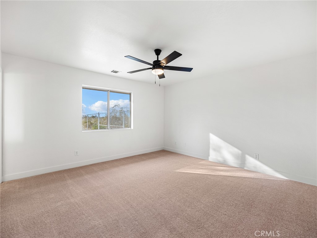 12780 Hacienda Road Phelan, CA 92371 - Photo 19 of 38 an empty room with a ceiling fan and a window