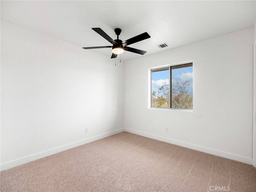 12780 Hacienda Road Phelan, CA 92371 - Photo 23 of 38 an empty room with a window and a fan