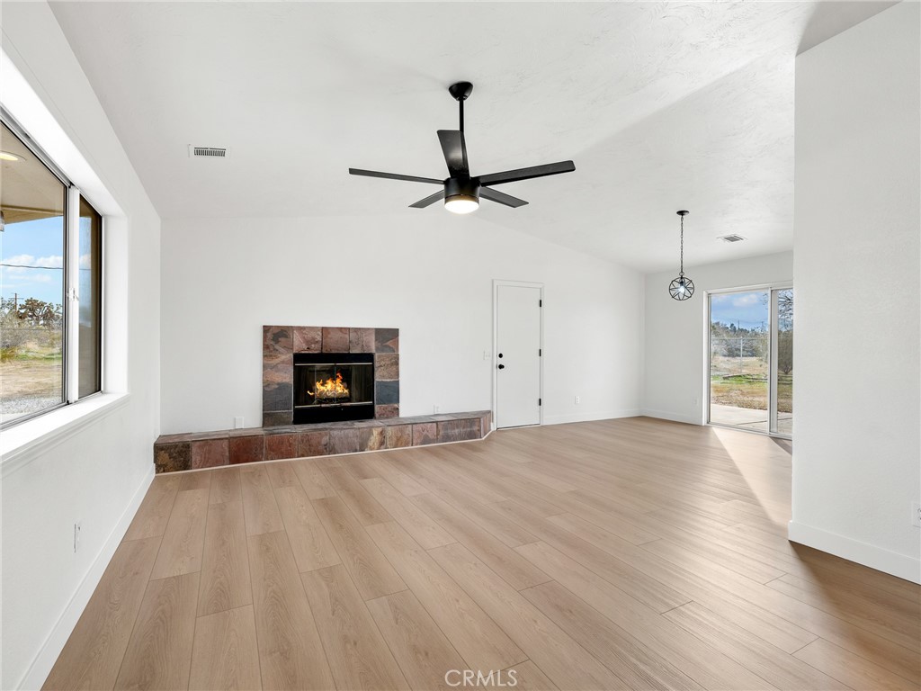 12780 Hacienda Road Phelan, CA 92371 - Photo 6 of 38 a view of empty room with wooden floor and fireplace