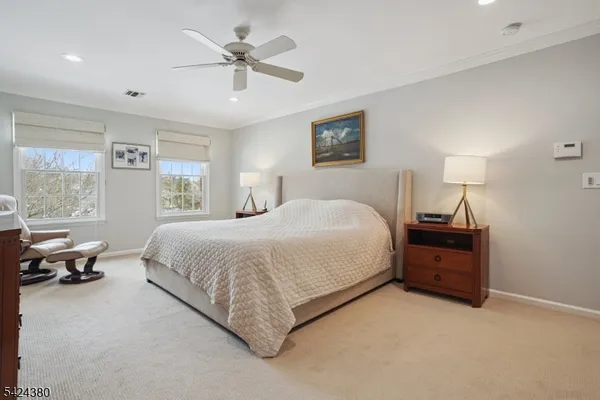 a spacious bedroom with a bed and a flat tv screen on the dresser
