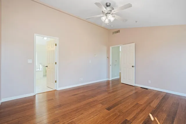 an empty room with wooden floor and ceiling fan