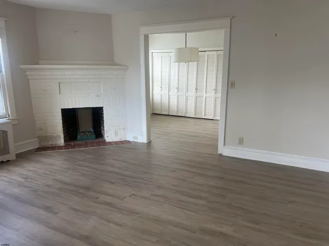 an empty room with wooden floor and fireplace