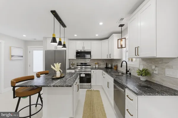 a kitchen with kitchen island granite countertop a sink a counter space appliances and cabinets
