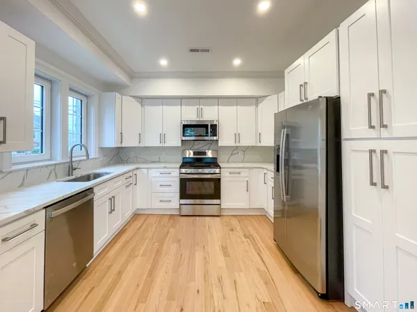 a kitchen with granite countertop a refrigerator stove top oven and sink