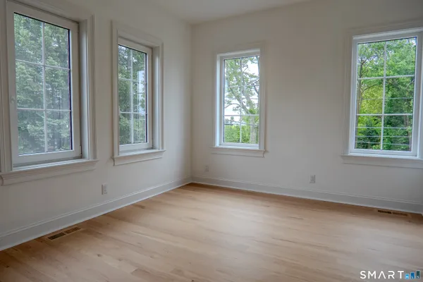 a view of an empty room with wooden floor and windows