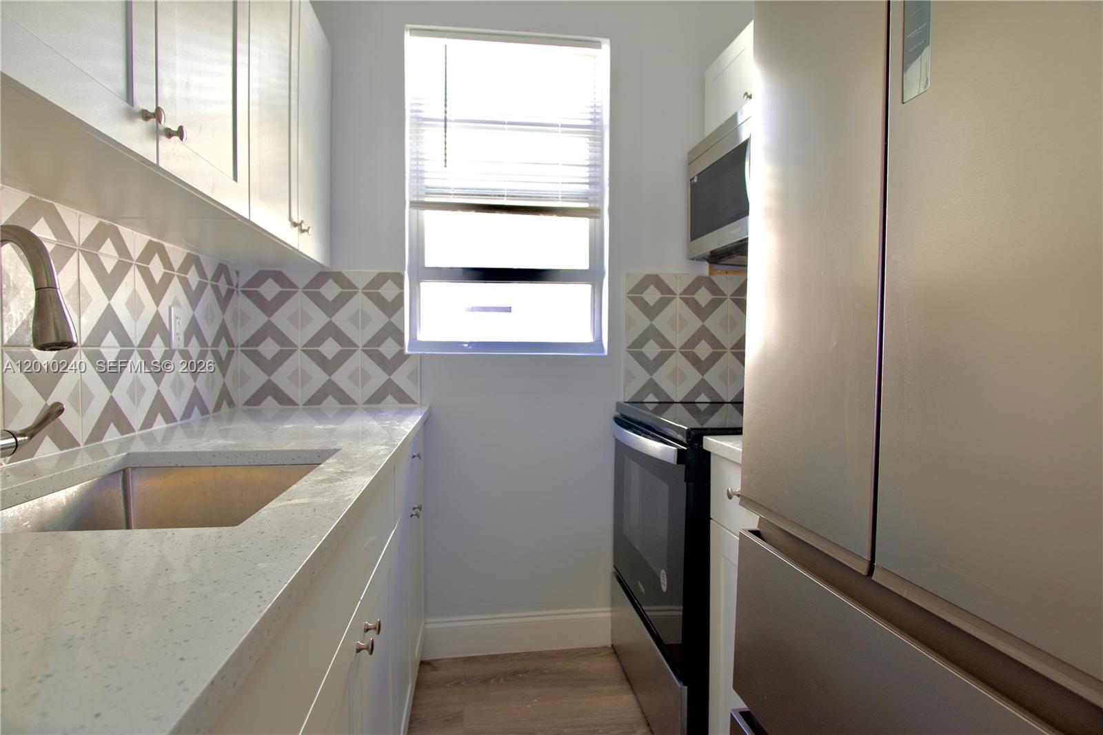 1142 Southwest 4th Street, Unit 17 Miami, FL 33130 - Photo 12 of 20 a kitchen with a refrigerator and a sink