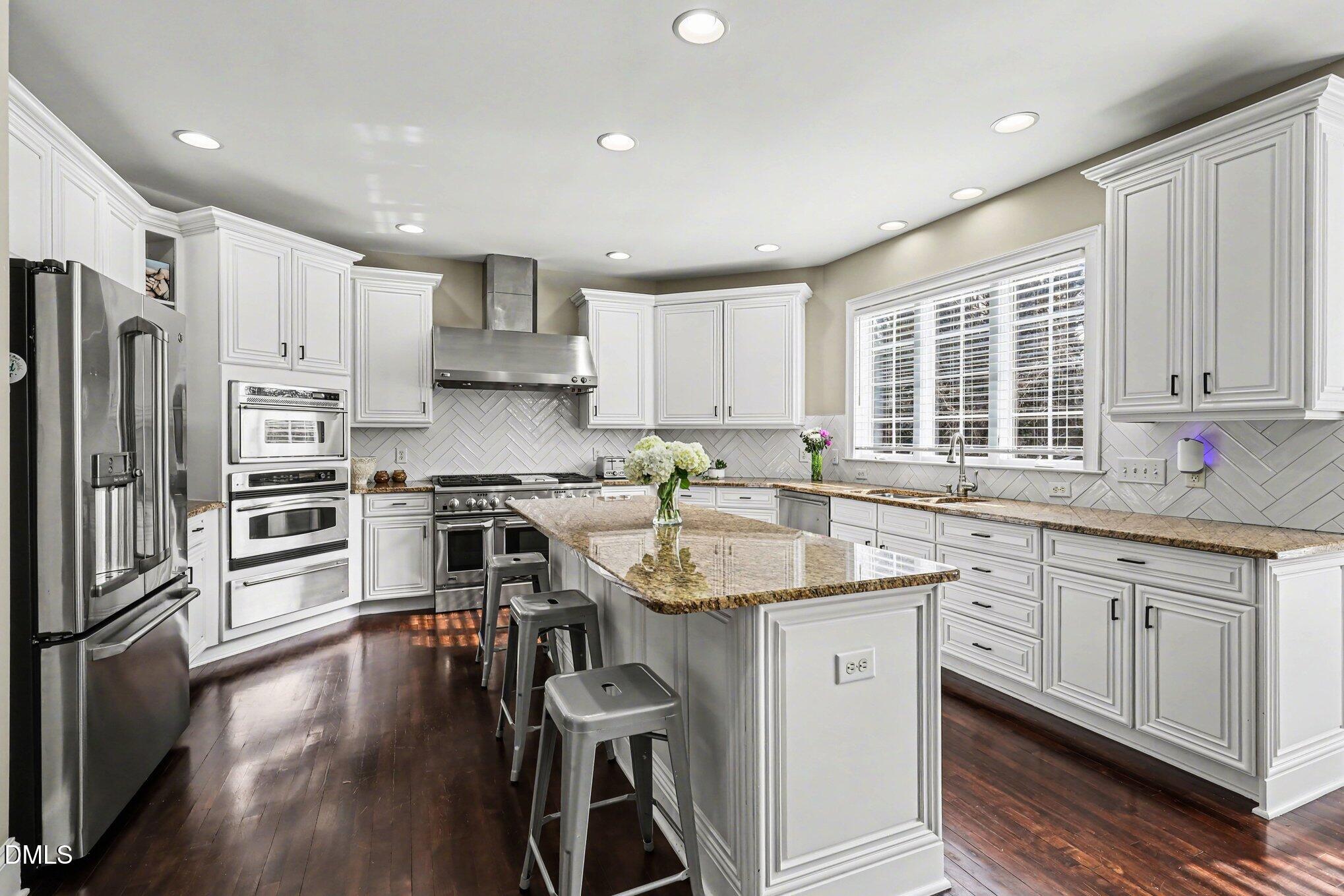 10643 Tarton Fields Circle Raleigh, NC 27617 - Photo 10 of 53 a kitchen with stainless steel appliances granite countertop a stove top oven a refrigerator a sink and dishwasher with wooden floor
