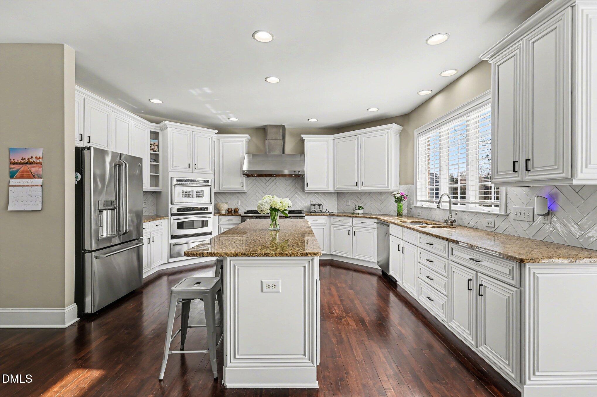 10643 Tarton Fields Circle Raleigh, NC 27617 - Photo 11 of 53 a kitchen with stainless steel appliances granite countertop a refrigerator a sink dishwasher a s stove top oven a large island with white cabinets and wooden floor