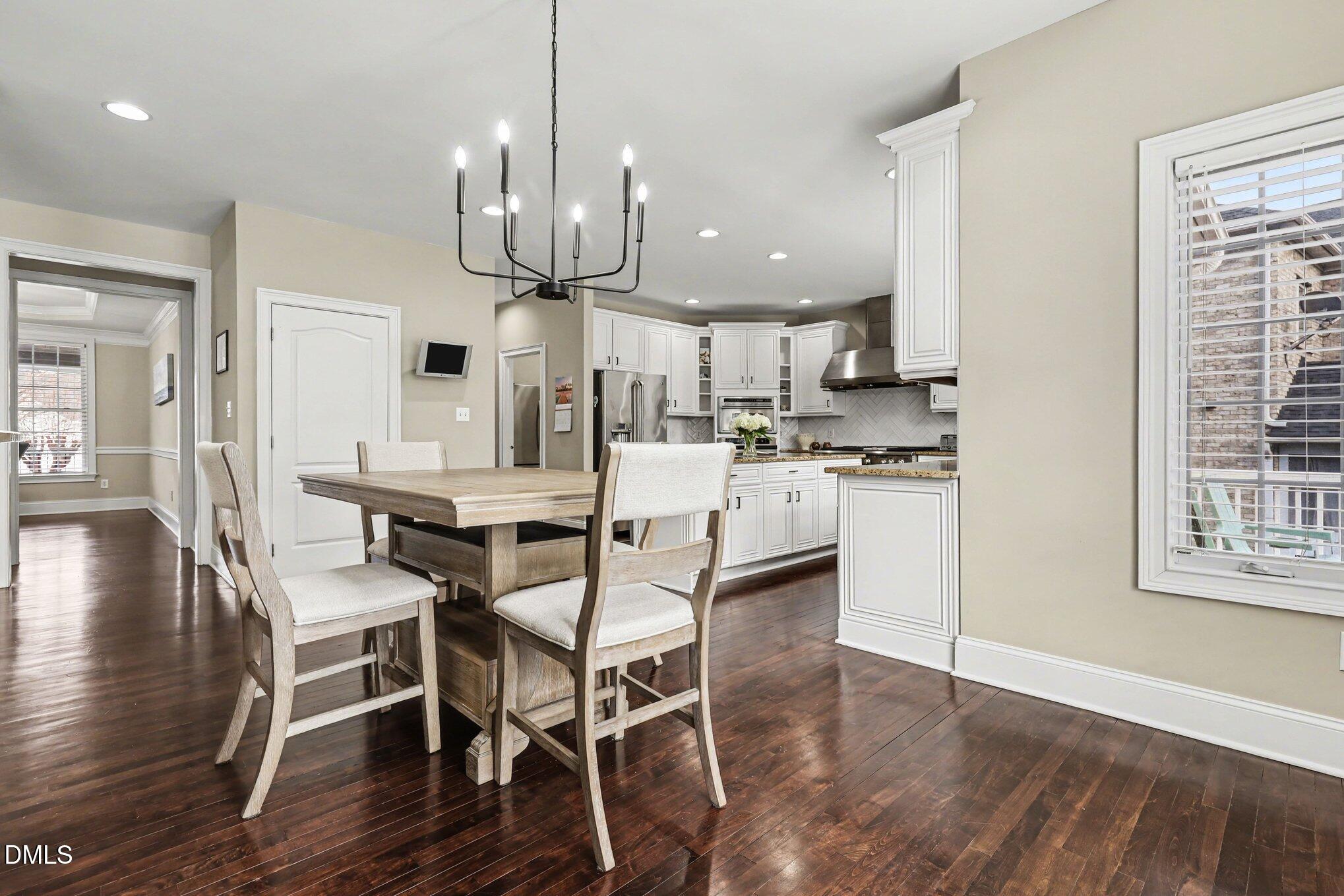 10643 Tarton Fields Circle Raleigh, NC 27617 - Photo 17 of 53 a kitchen with stainless steel appliances kitchen island granite countertop a wooden floor and white cabinets