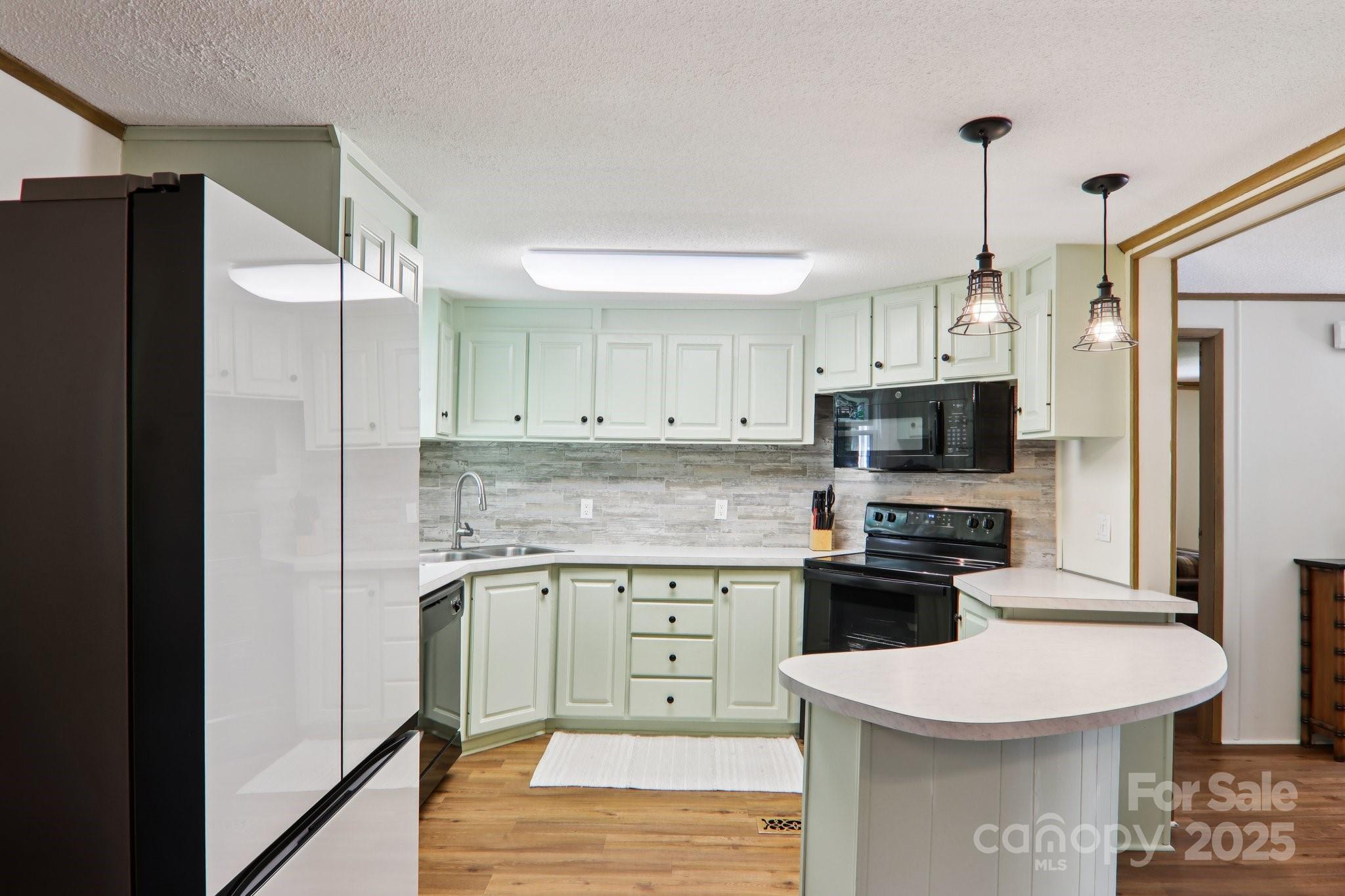 226 Cranbrook Circle Hendersonville, NC 28792 - Photo 14 of 47 a kitchen with stainless steel appliances a sink stove refrigerator and white cabinets with wooden floor