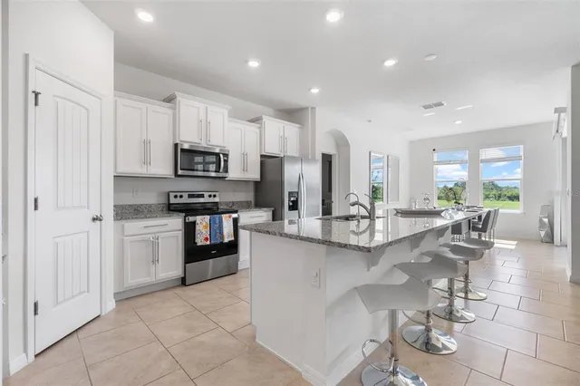 a kitchen with stainless steel appliances granite countertop a sink refrigerator and cabinets