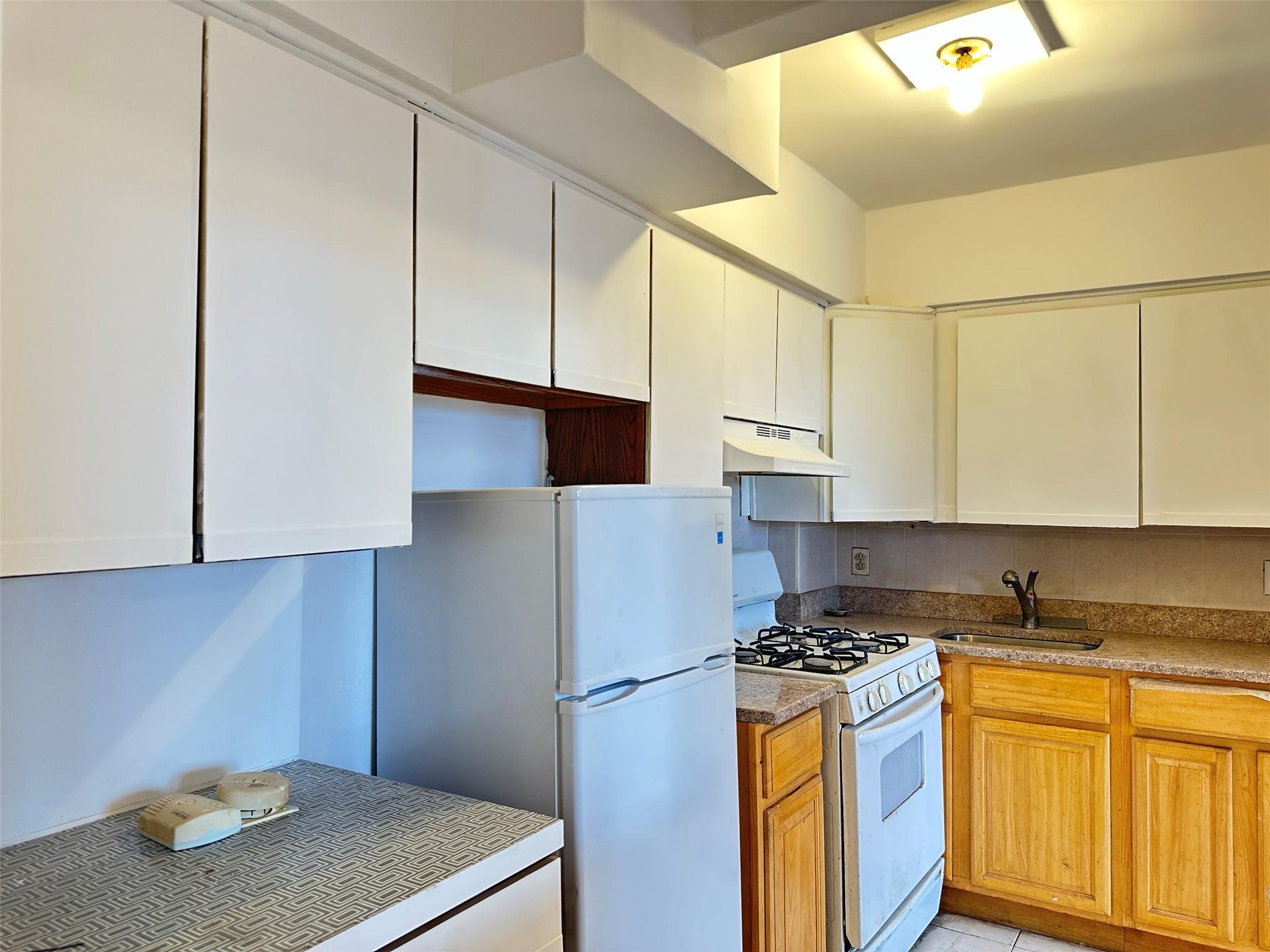 152-72 Melbourne Avenue, Unit 2P Queens, NY 11367 - Photo 3 of 8 Kitchen featuring white appliances, under cabinet range hood, and decorative backsplash