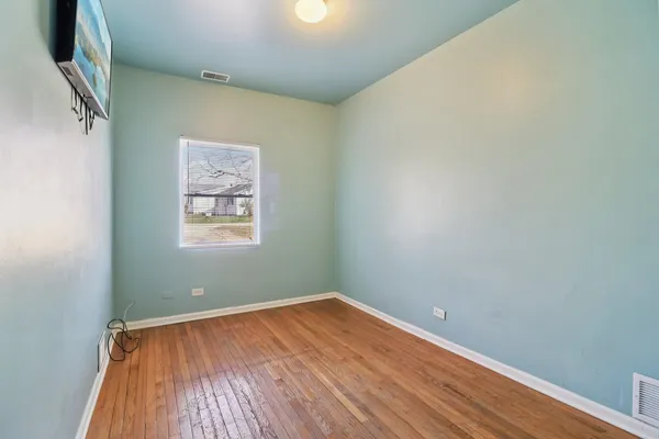 an empty room with a window and wooden floor