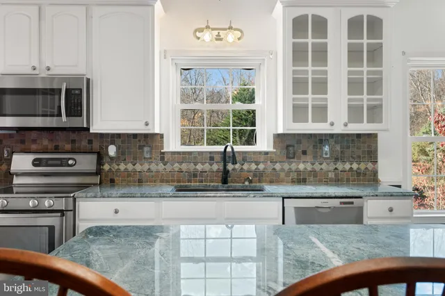 a kitchen with stainless steel appliances granite countertop a stove a sink and a microwave