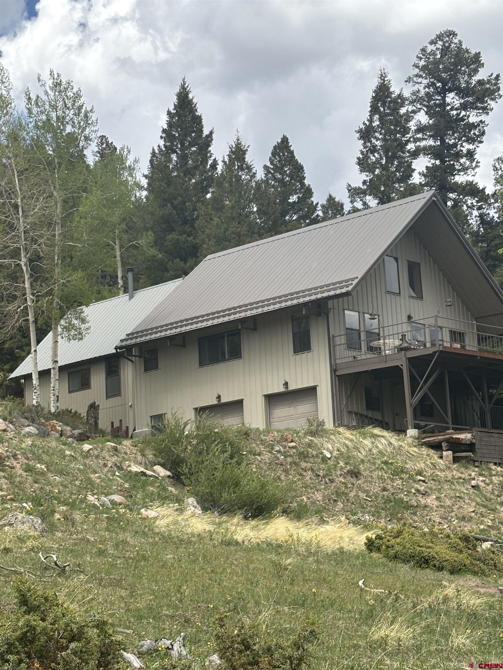 1113 Spring Street Del Norte, CO 81132 - Photo 10 of 43 a backyard of a house with large trees and a yard