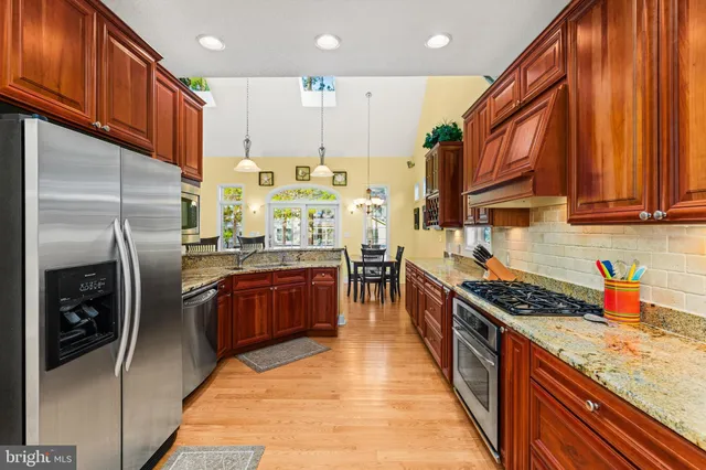 a kitchen with stainless steel appliances granite countertop a refrigerator a stove and a sink
